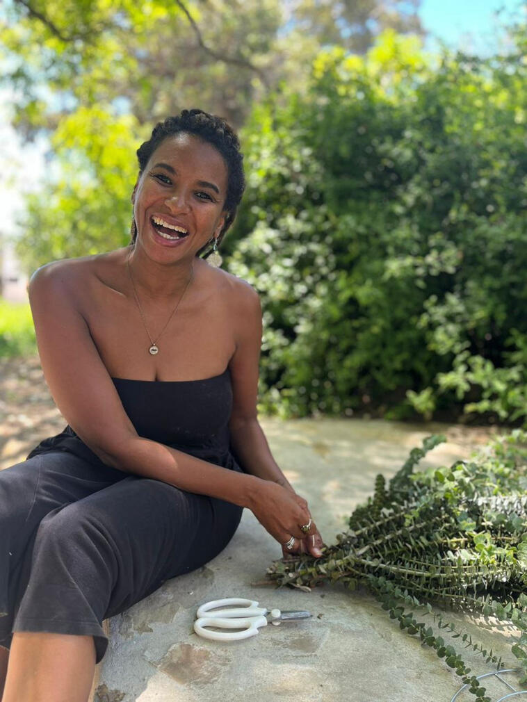 Simone Clarke, The Lens of Love Simone Clarke laughing outdoors in McGregor, making a Christmas wreath with freshly cut greenery.